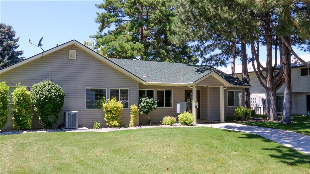 a gray house with a lawn and trees