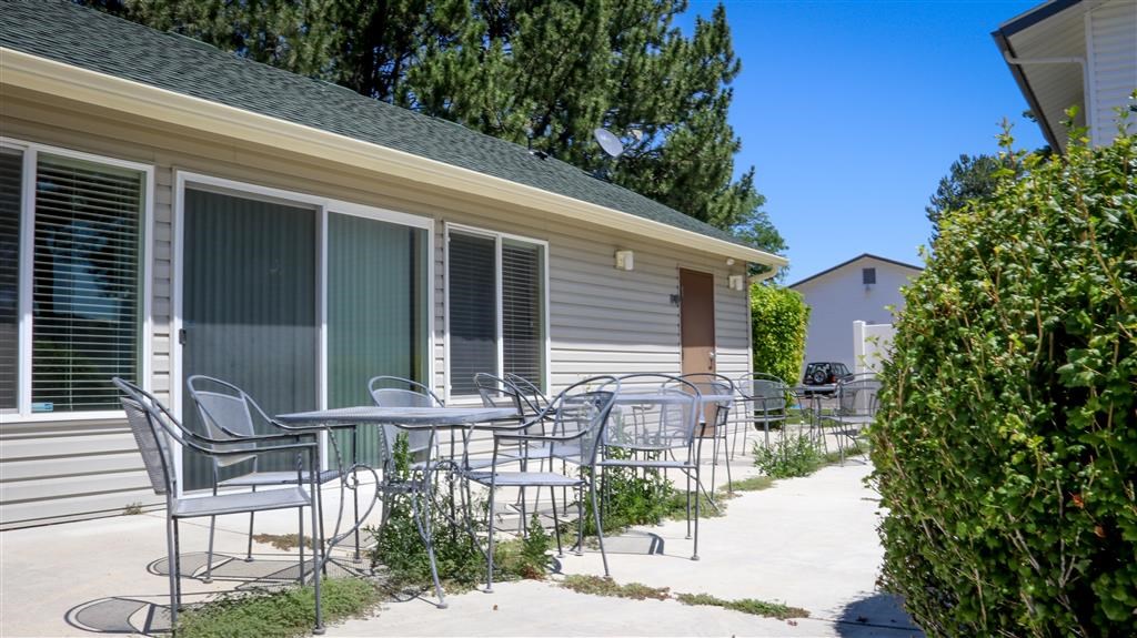 a patio with chairs and tables outside of a house