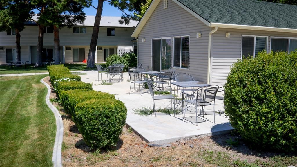 a patio with tables and chairs in front of a house