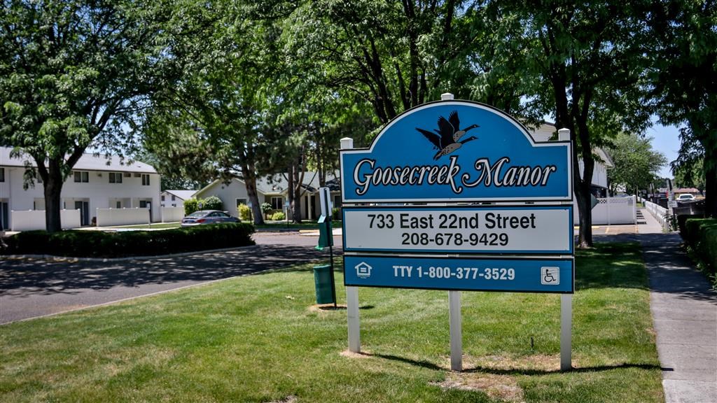a blue sign sitting in the grass next to a street