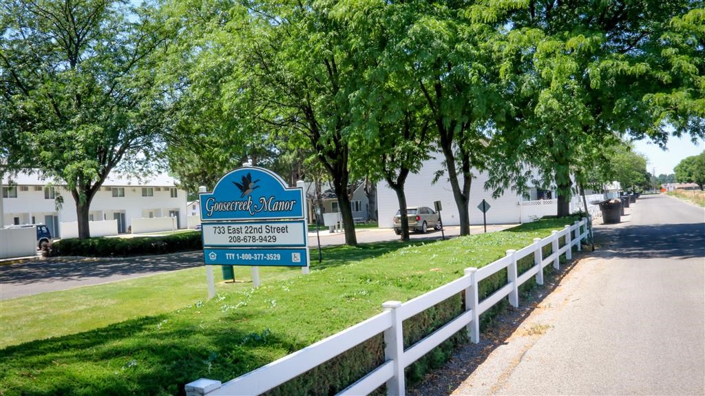 a blue sign sitting on the side of a road next to a fence