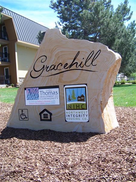 a rock in the grass with a sign on it
