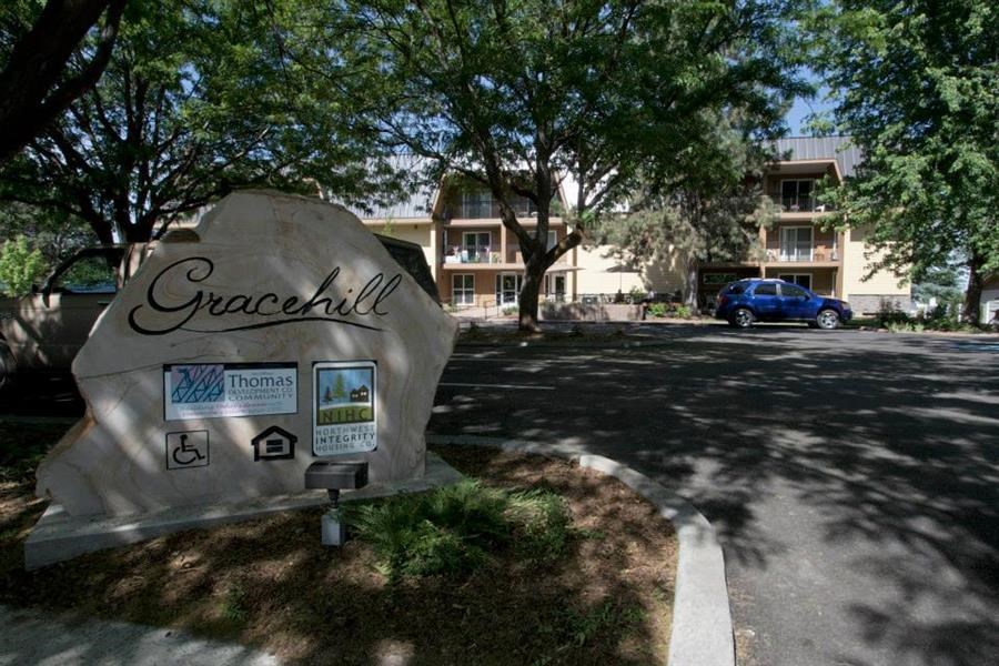 a rock sign sitting in the grass next to a street