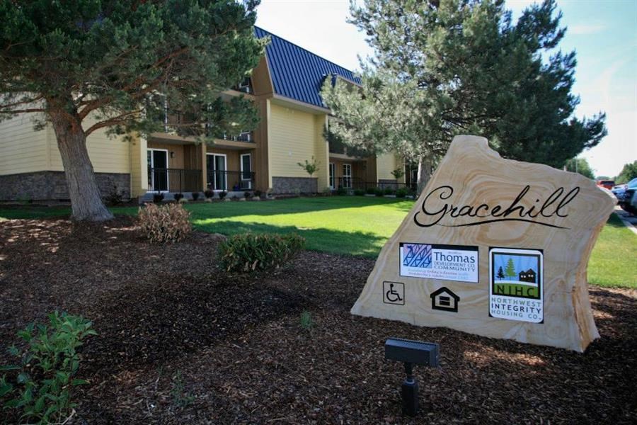 a sign in front of a house with a lawn and trees