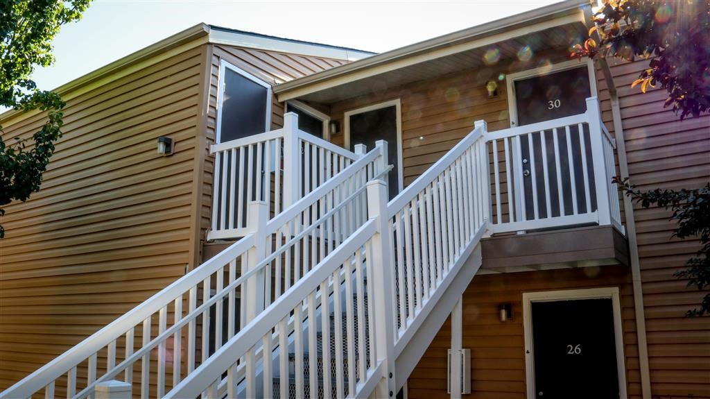 a wooden house with a white railing on the stairs