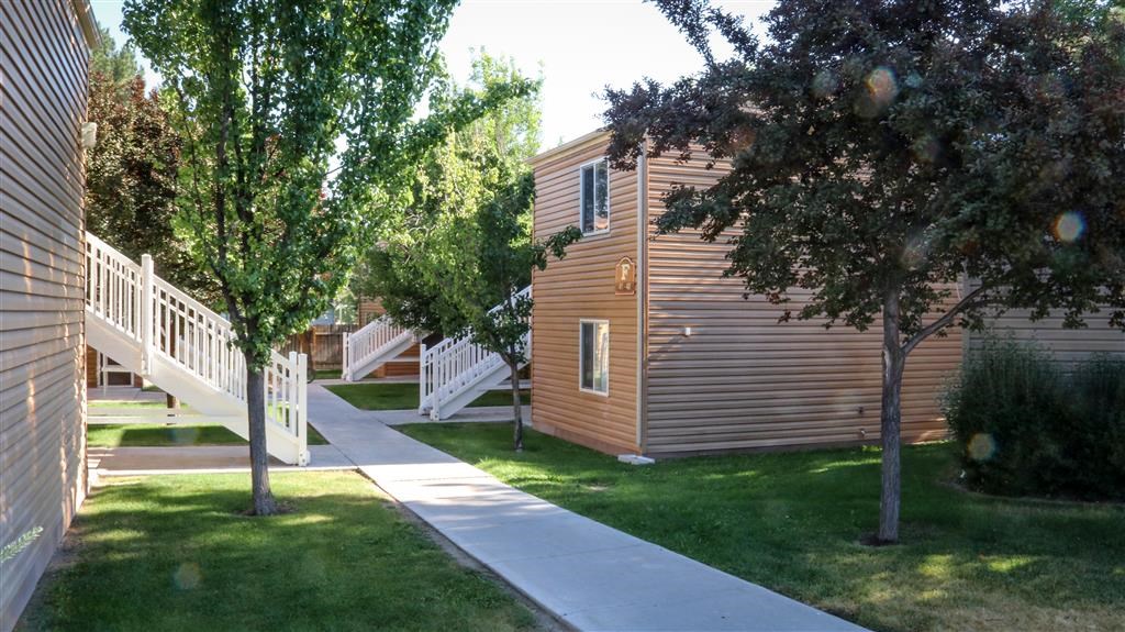 a small wooden building with a sidewalk and trees