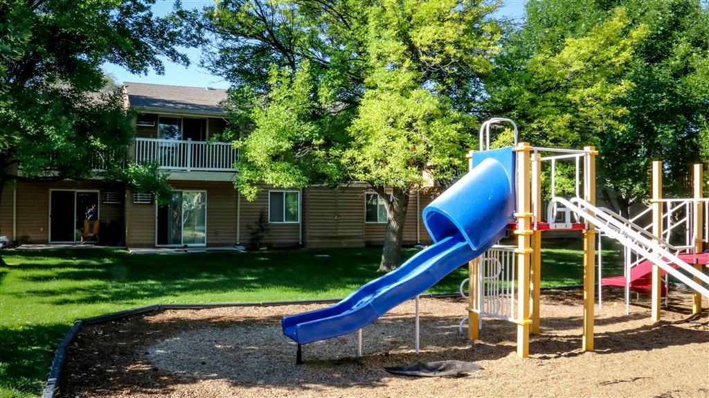 a playground with a blue slide in front of a house