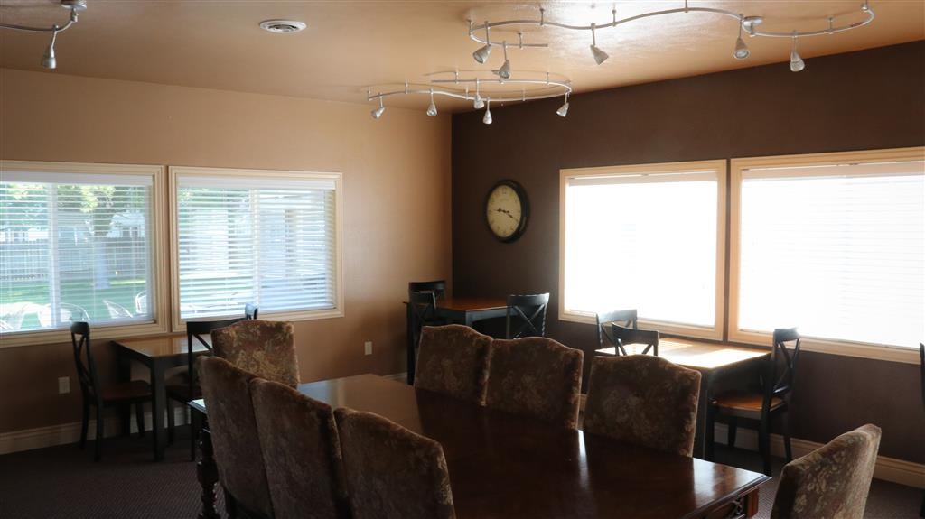 a dining room table with chairs and a clock on the wall