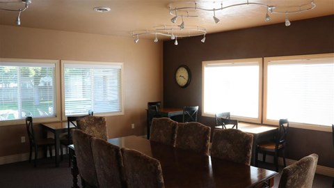 a dining room table with chairs and a clock on the wall