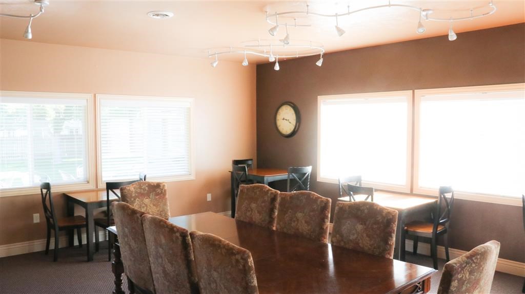 a dining room table with chairs and a clock on the wall