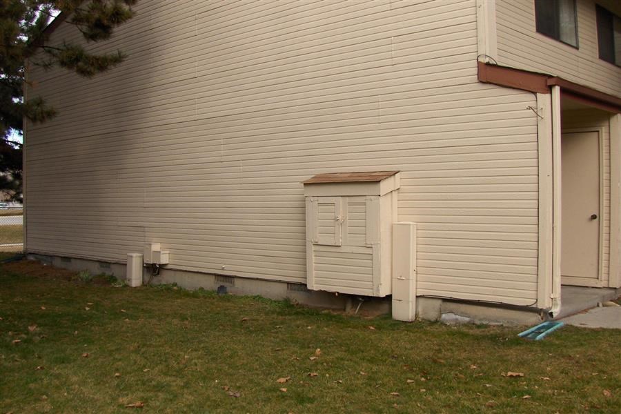 the side of a house with a trash can next to it