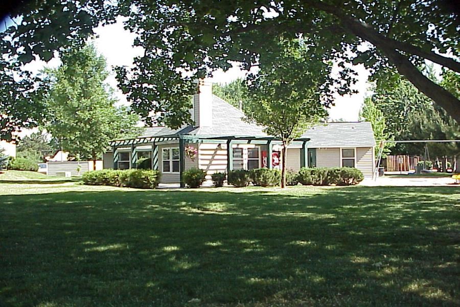 a small white house with a lawn and trees