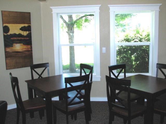 a dining room with a table and chairs and two windows