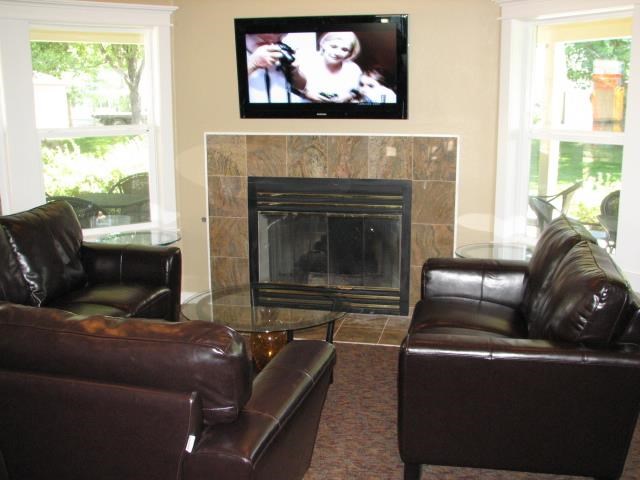 a living room with leather furniture and a tv over a fireplace
