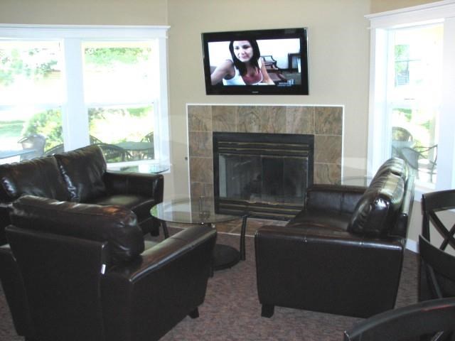 a living room with leather furniture and a tv over a fireplace