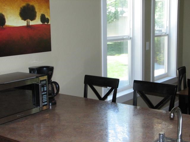 a kitchen counter with a microwave and chairs