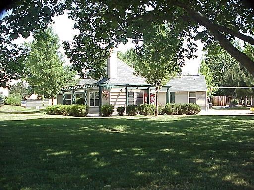 a small house with a lawn and trees in front of it