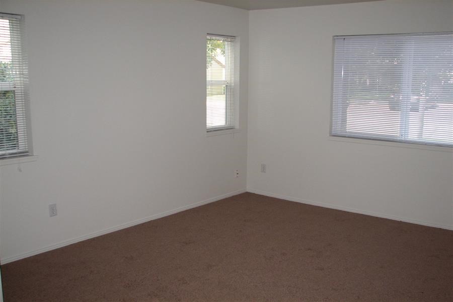 an empty room with two windows and a carpet
