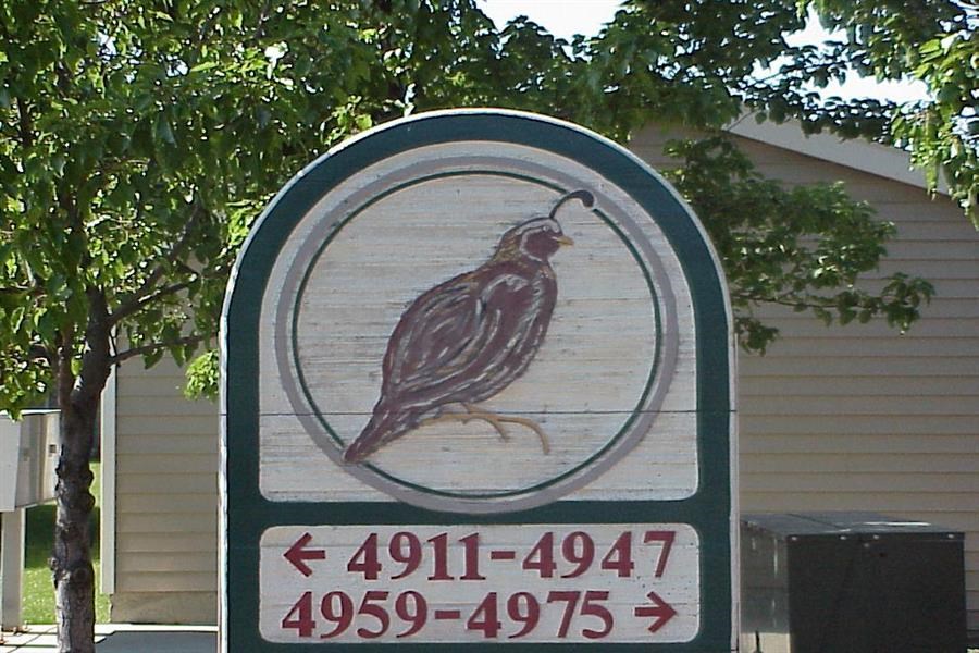 a sign with a bird on it in front of a house