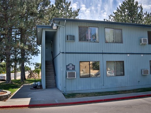 the front of a blue building with stairs and trees