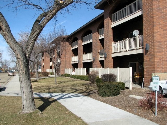 an apartment building with a sidewalk and a tree