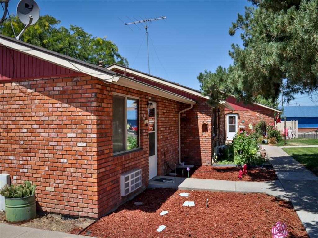 the front of a brick house with a sidewalk and a tree