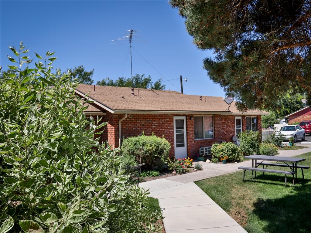 a small brick house with a sidewalk and a picnic table