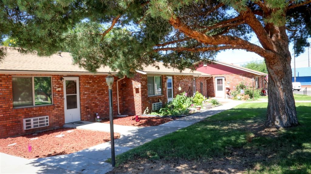 a red brick house with a tree in front of it