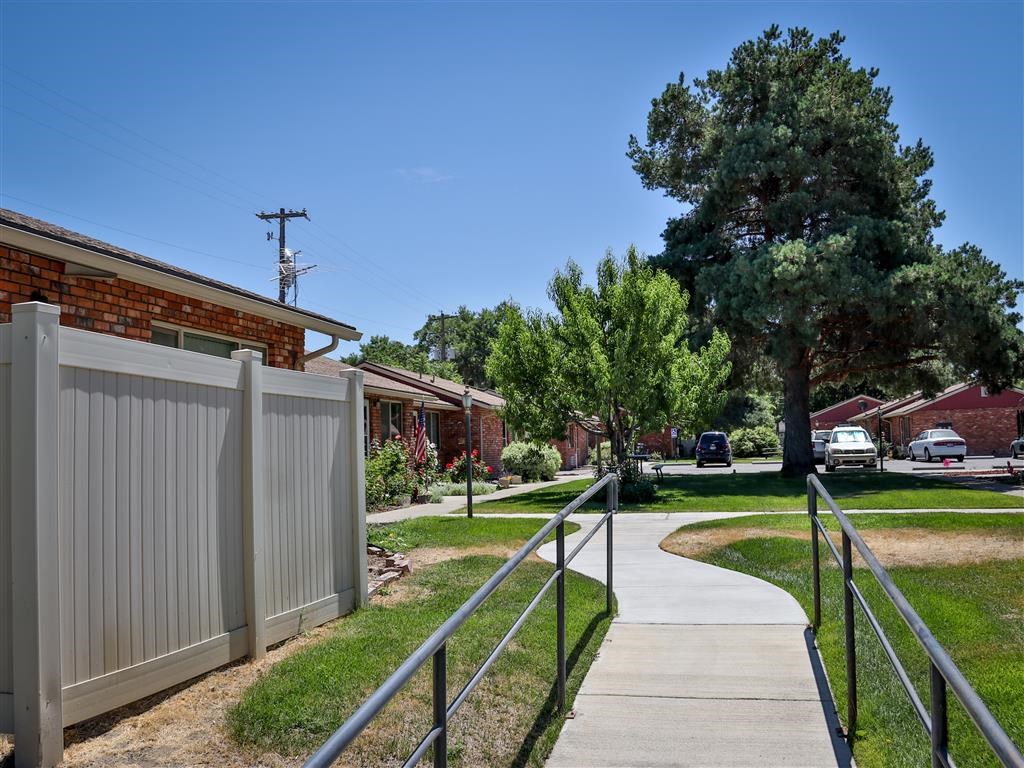 a sidewalk in front of a house with a fence