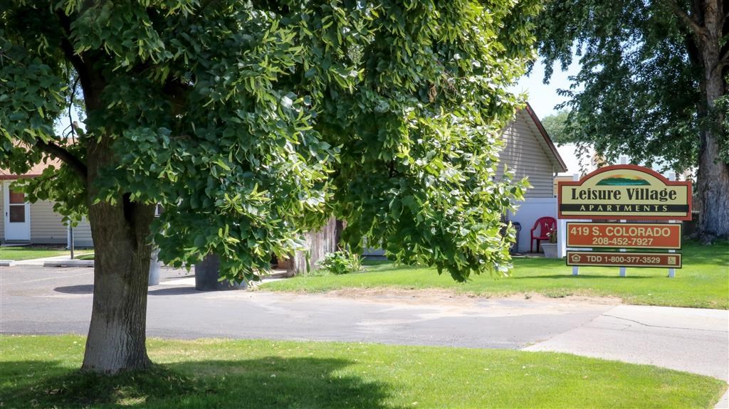 a sign in front of a tree in the grass