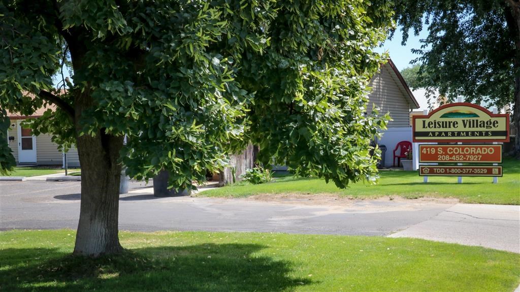 a sign in front of a tree in the grass