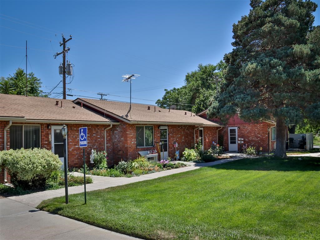 the front of a brick building with a lawn and sidewalk
