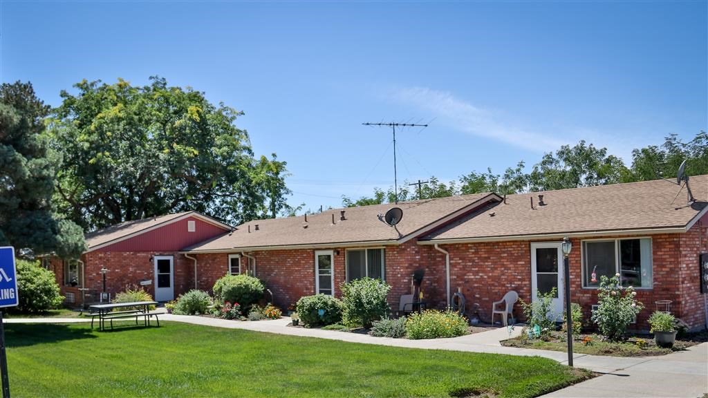 a red brick house with a lawn and a table and chairs