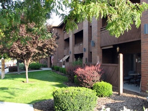 an apartment building with a lawn and trees