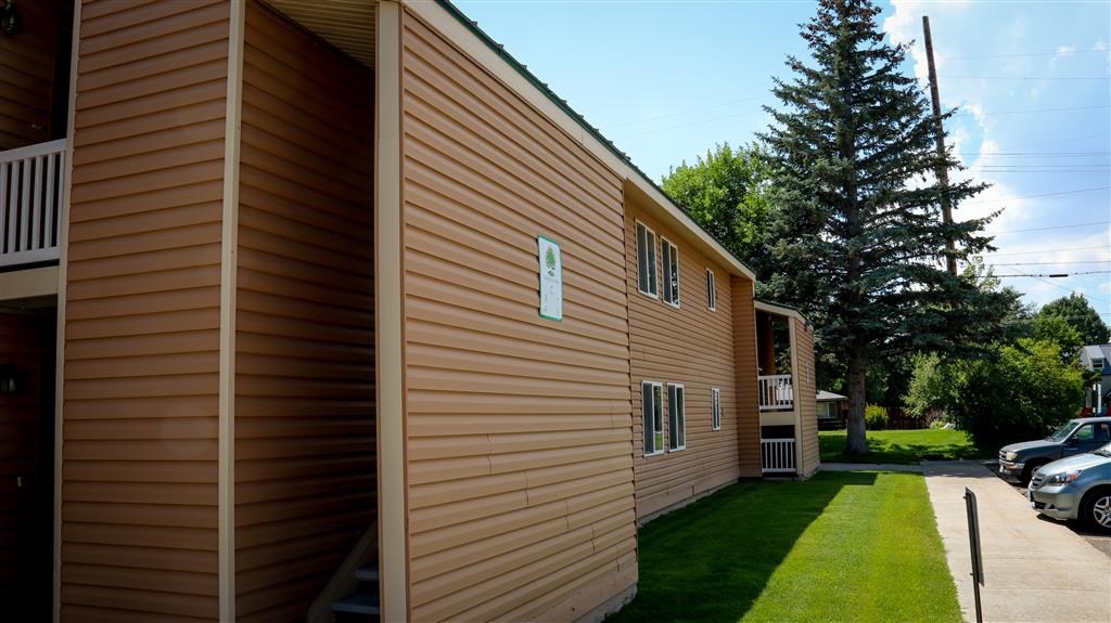 the side of a house with a yard and a tree