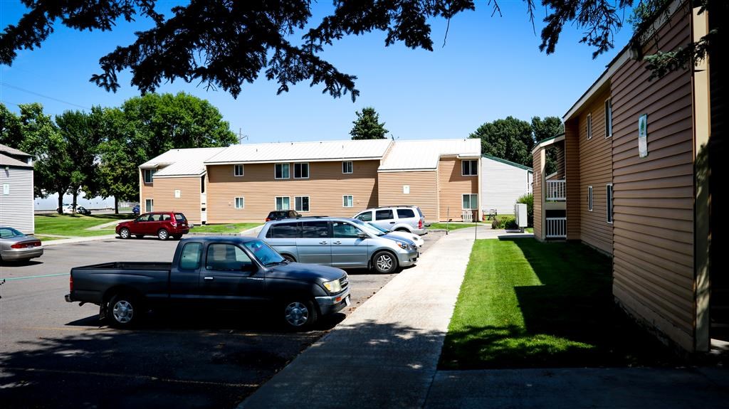 a parking lot with cars parked in front of apartments
