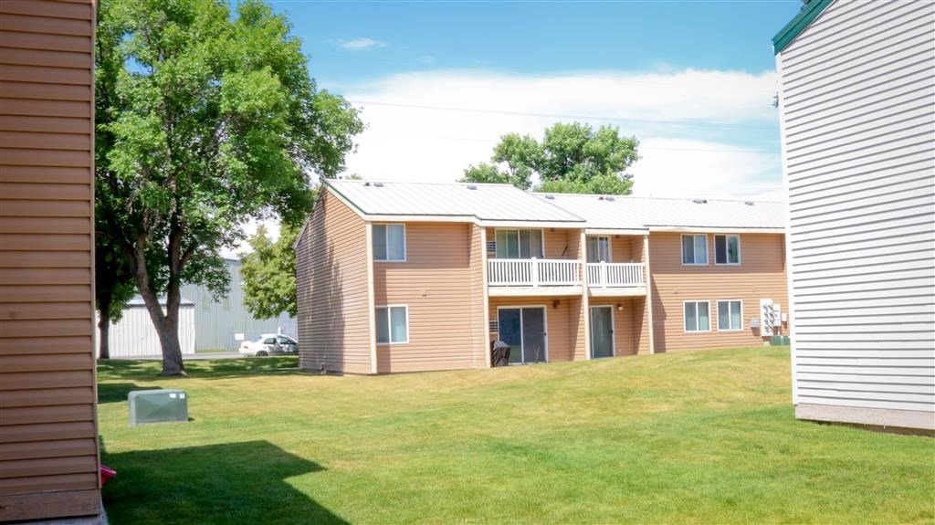 an apartment building with a yard and a tree