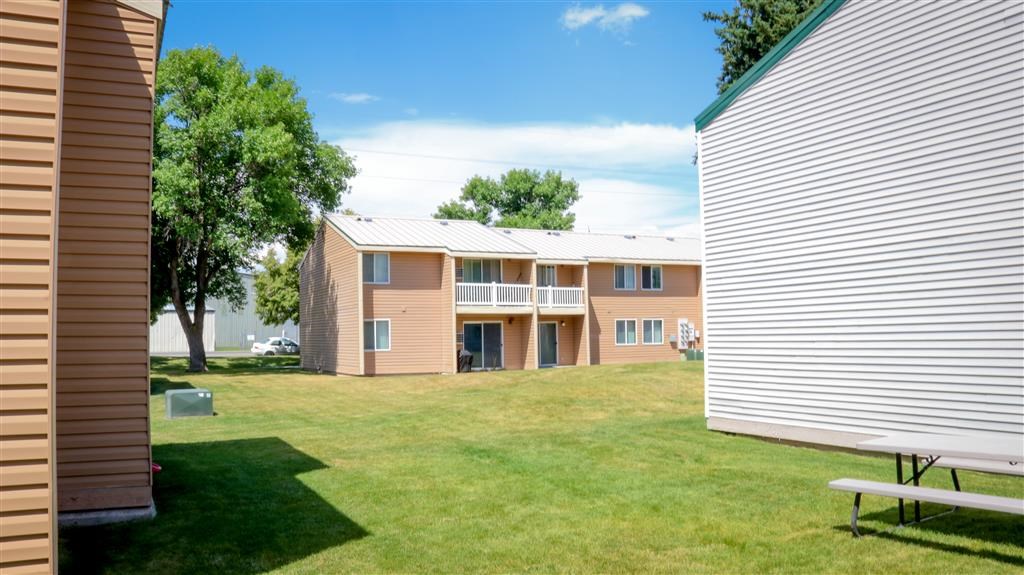 an apartment building with a grass yard and a picnic table