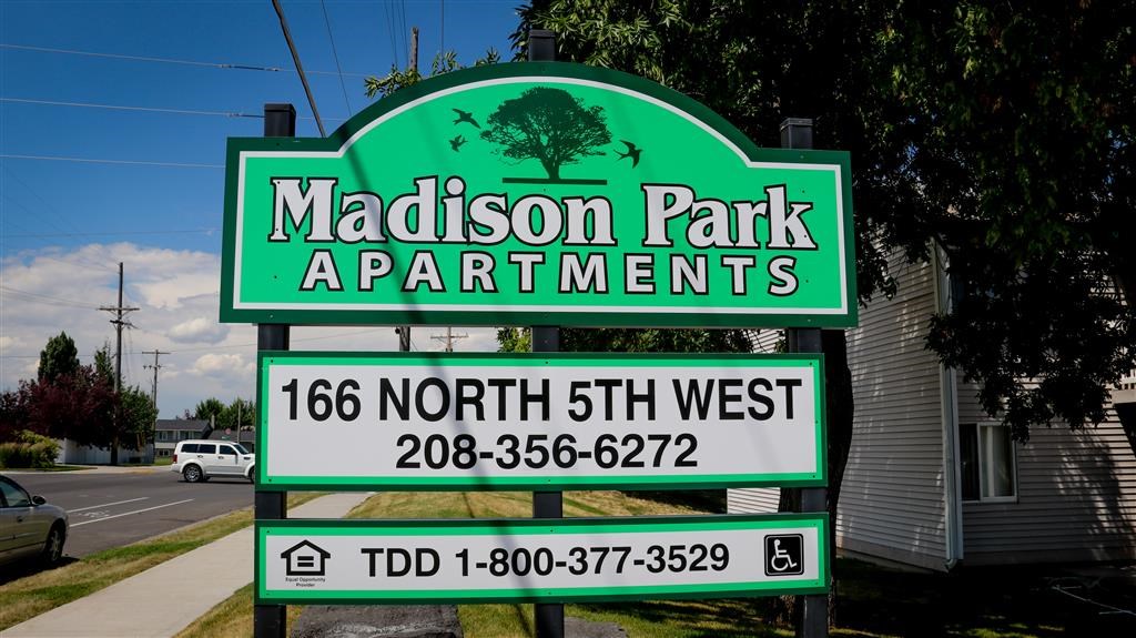 a sign for madison park apartments on the side of the street