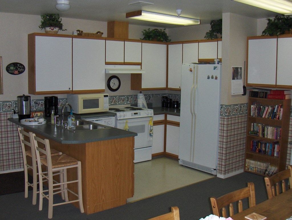 a kitchen with white appliances and a counter with chairs
