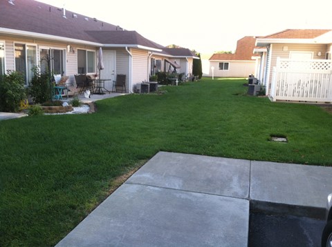 a yard with a concrete walkway in front of a house