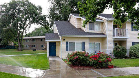 a yellow house with a porch and some flowers