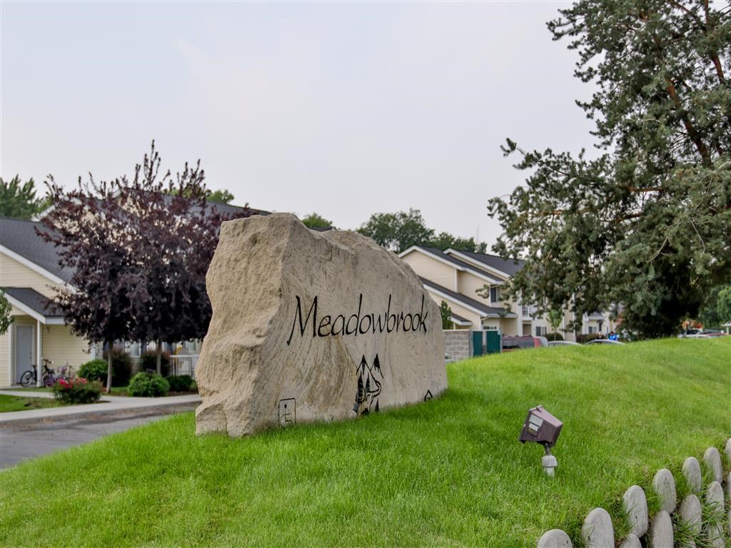 a large rock sitting on the grass in front of a sign