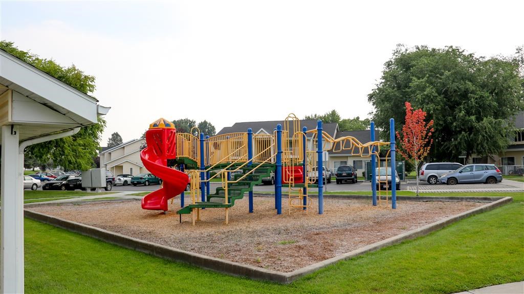 a playground with a red slide in a park