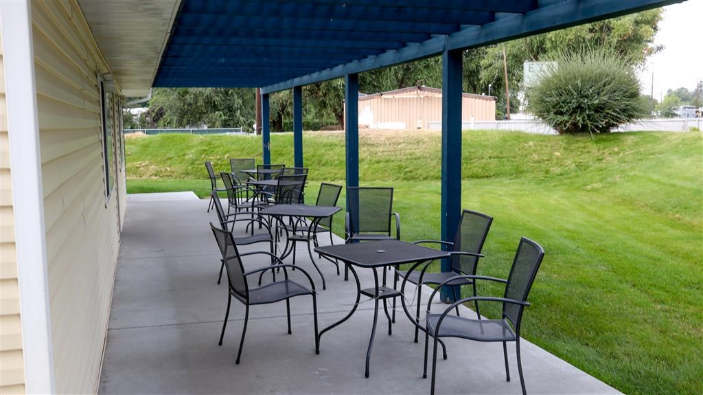 a patio with tables and chairs under a blue roof