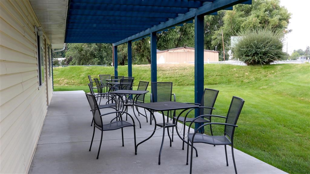 a patio with tables and chairs under a blue roof