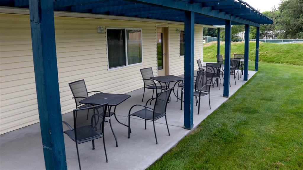 a patio with tables and chairs on the side of a building