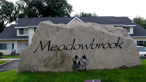 a large rock with the word on it in front of a house