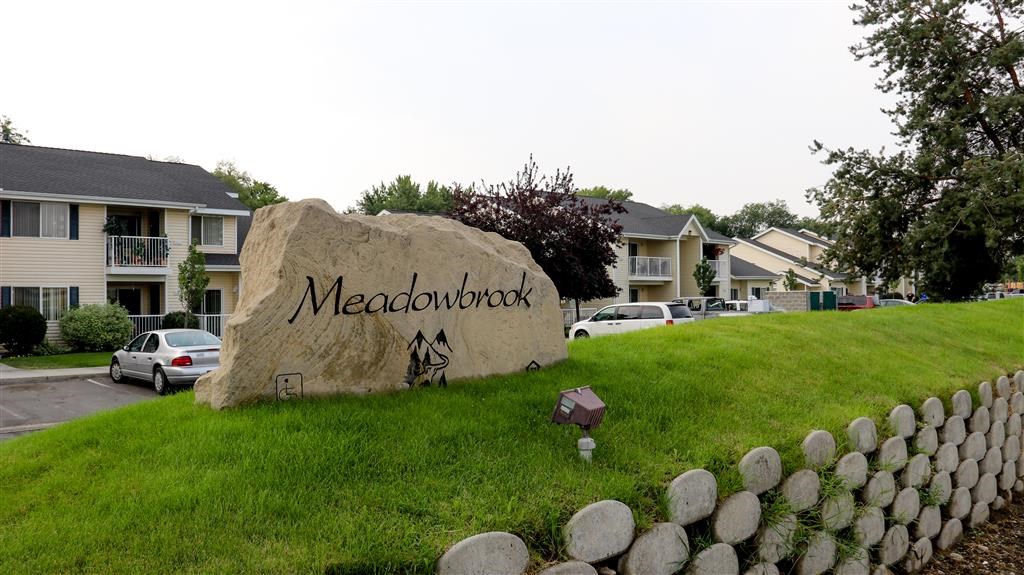 a rock sitting on the grass in front of a sign