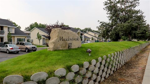 a stone sign sitting on the grass next to a fence
